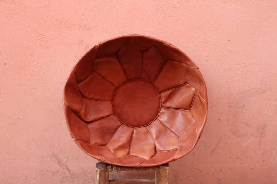 Handcrafted leather pouf, artisan-made in Morocco, with intricate stitching and a natural brown finish, suitable for decor or seating