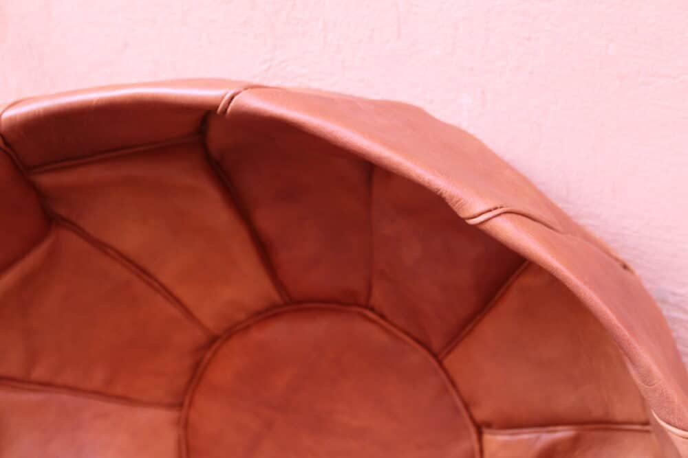 Handcrafted leather pouf, artisan-made in Morocco, with intricate stitching and a natural brown finish, suitable for decor or seating