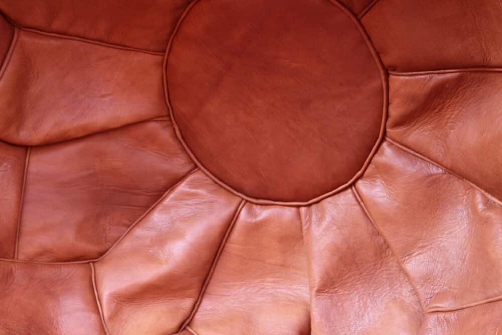 Handcrafted leather pouf, artisan-made in Morocco, with intricate stitching and a natural brown finish, suitable for decor or seating