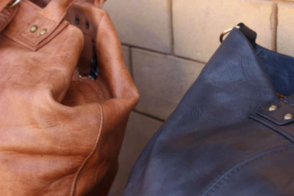 Premium Leather Messenger Bag on a rustic wooden table with travel accessories.