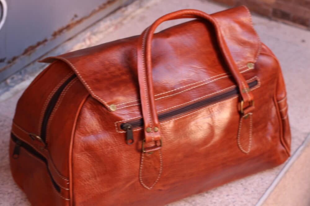Detail of adjustable shoulder strap and sturdy handles of the travel bag.