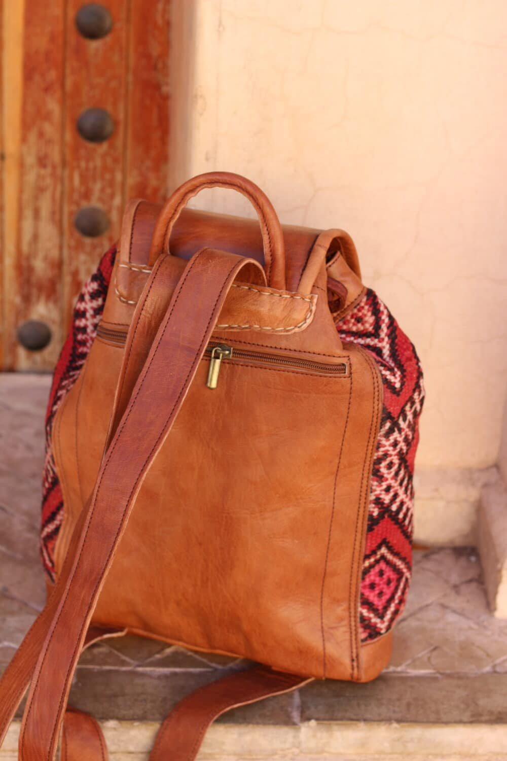 Unique leather backpack purse with adjustable straps on a wooden surface