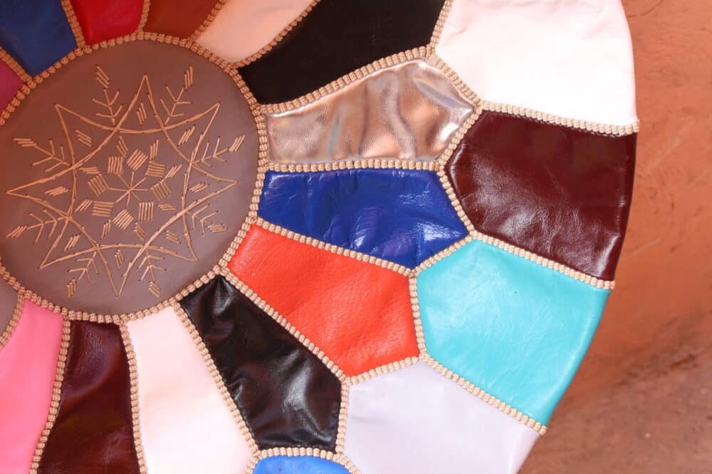 A Multicolor Moroccan Leather Pouf showcasing a mosaic-style design, handcrafted with genuine leather.