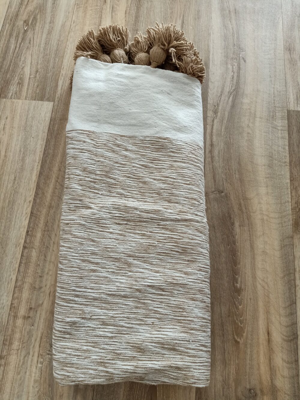 Natural handwoven pom-pom blanket with earthy tones and intricate weaving.